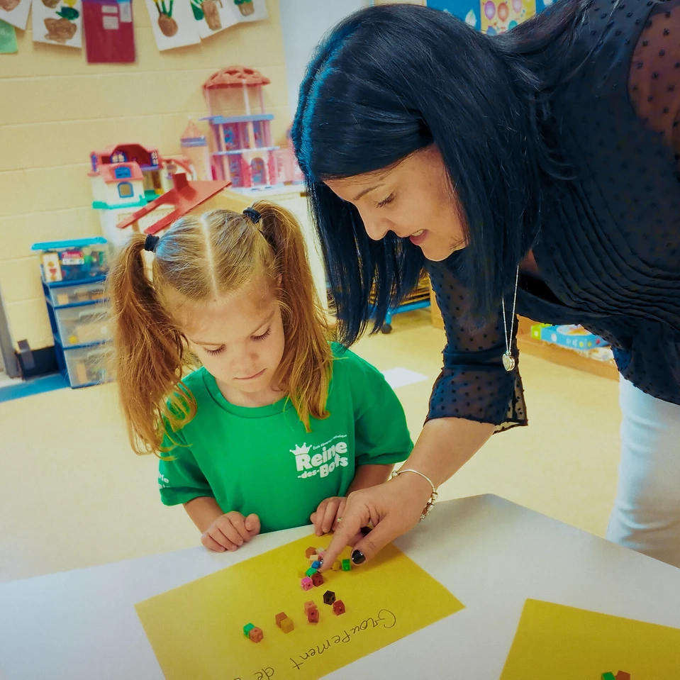 une enseignante qui aide une jeune élève dans un bricolage